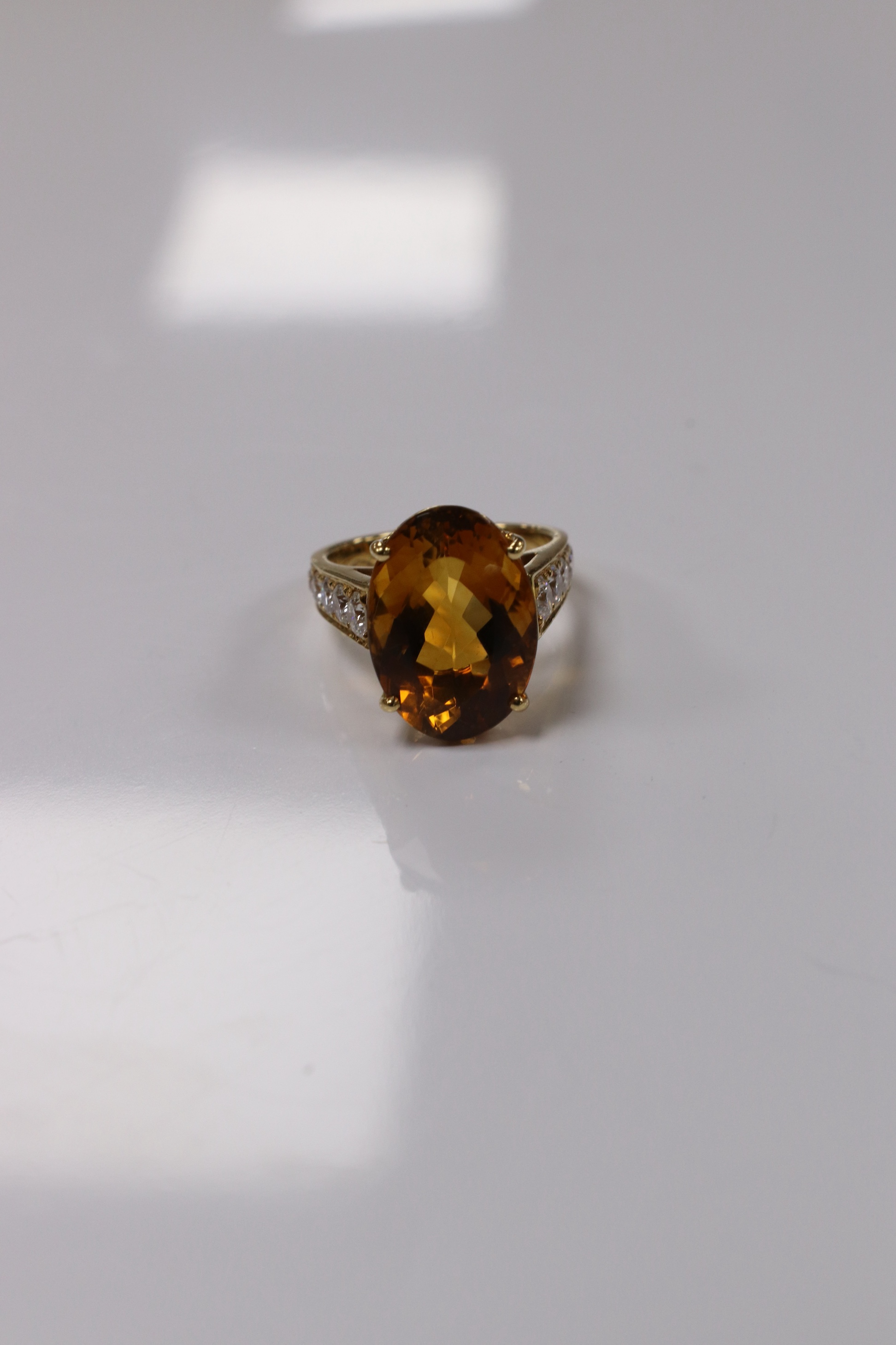 A modern 18k and single stone oval cut citrine set dress ring, with ten stone graduated diamond set shoulders, size K, gross weight 7,7 grams. Condition - good